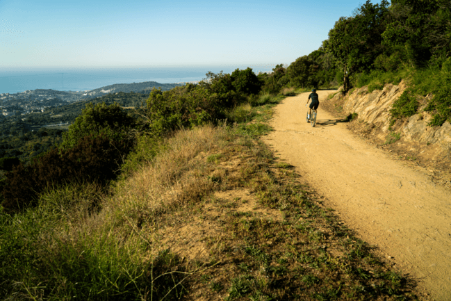 A cyclist on a dirt track overlooking the sea